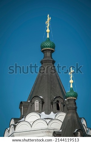 black domes of an Orthodox church with gilded crosses against a blue sky