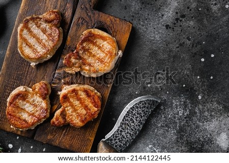 Medallions steaks from pork tenderloin, on black dark stone table background, top view flat lay, with copy space for text