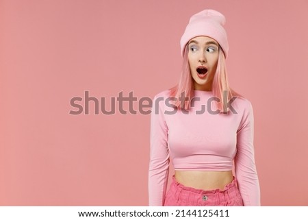 Young shocked amazed woman 20s with bright dyed rose hair wearing rosy top shirt hat look aside isolated on plain light pastel pink color background studio portrait People lifestyle fashion concept