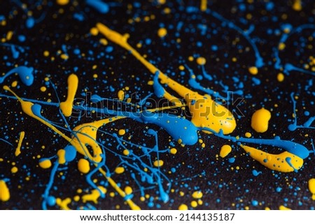Blue and yellow paint drops on black canvas. Ukrainian flag concept .