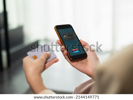 Beautiful businesswoman payment by credit card on mobile phone for online shopping, copy space at background, selective focus at credit card on mobile phone. Young woman shopping online in home office