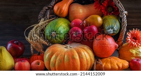Thanksgiving autumn still life. Pumpkins, winter squash, apples, ears of wheat, nuts, and flowers spill out of a wicker basket in fall. Rich harvest beautiful picture for a calendar, postcard, poster
