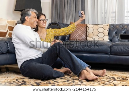 Father and daughter vlogging or video chatting using mobile phone at home