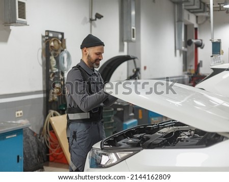 the man works at a car service station. car repair shop worker Royalty-Free Stock Photo #2144162809