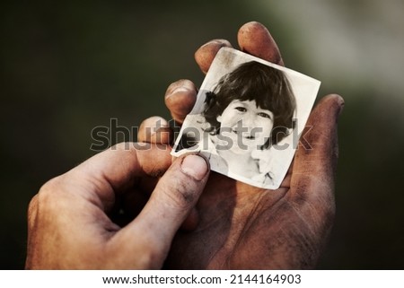 I miss my son so much. A dirty hand holding a black and white picture of a little boy.