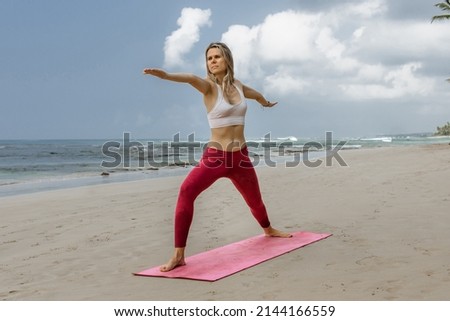 Beautiful young woman stretching during yoga on the beach