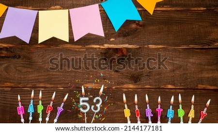 Top view, birthday decorations from letters of candles with fire and festive garlands, save space. Happy birthday background with number 53 on a brown board table. happy birthday to fifty three
