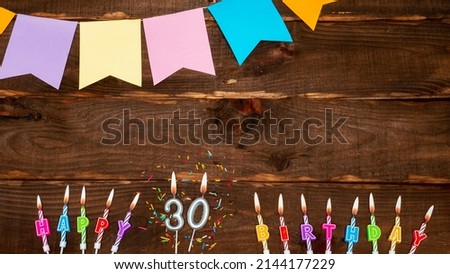 Top view, birthday decorations from letters of candles with fire and festive garlands, save space. Happy birthday background with number 30 on brown board table. happy birthday for thirty years old