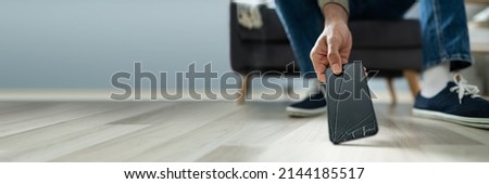 Close-up Of A Man Picking Up The Broken Smart Phone From Hardwood Floor