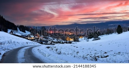 Winter landscape in the mountains, view from the hill to the valley at sunset.