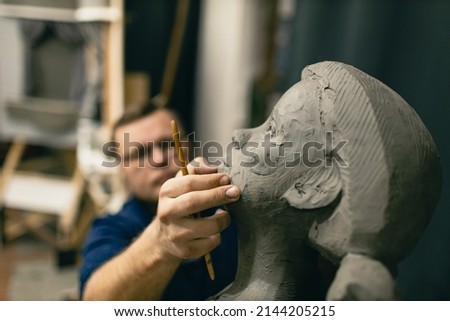 Man sculptor creates sculpt bust clay human woman sculpture. Statue craft creation workshop. Royalty-Free Stock Photo #2144205215