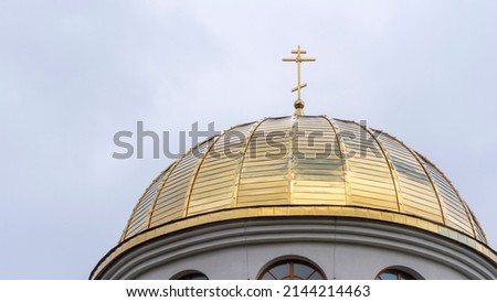 Close-up view of golden yellow dome of church with orthodox cross on dramatic sky background. Space for text. Worship concepts.