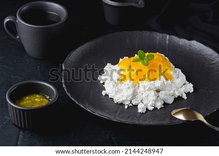 Lemon jam with cottage cheese in black bowl closeup