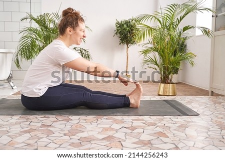 Young woman going yoga exercise at home. Health care online lessons. Indoor fitness workout. Remote sport trainer. Morning activity. Floor pilates mat. Female person lifestyle. Asana pose Royalty-Free Stock Photo #2144256243