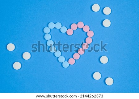 A heart of pink and blue pills on a blue background. The concept for Pharmacy Day, Supplements and Cardiopreparations . High quality photo