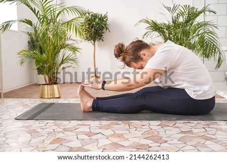 Young woman going yoga exercise at home. Health care online lessons. Indoor fitness workout. Remote sport trainer. Morning activity. Floor pilates mat. Female person lifestyle. Asana pose Royalty-Free Stock Photo #2144262413