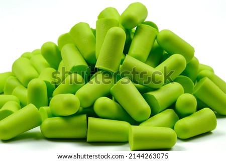 Lots of soft light green foam earplugs on a white background. Soft foam ear plugs.Close-up.The concept of getting rid of noise in a loud place, hearing protection.High quality photo