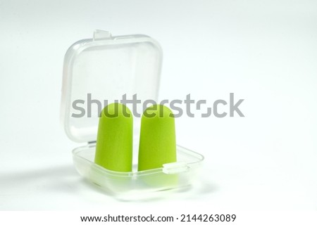 Soft light green foam earplugs in a plastic container on a white background. Close-up.The concept of getting rid of noise in a noisy place, hearing protection.High quality photo
