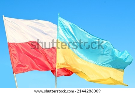 Developing waving Polish and Ukrainian flags on a blue peaceful sky, support for friendly countries  war in Ukraine