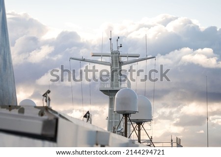 Shipping sea car ferry radar system on boat mast, satellite system with sunset in dramatic sky behind over ocean. Royalty-Free Stock Photo #2144294721