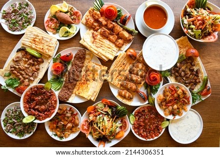 Delicious meat kebab with fresh vegetable salad served with variety of Turkish dishes and appetizers. Top view of assorted Turkish food and meze, tasty and healthy Mediterranean cuisine. Royalty-Free Stock Photo #2144306351