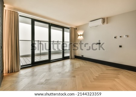 The interior of an empty spacious room with a panoramic window and access to the balcony