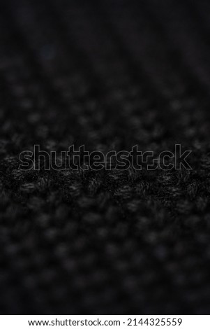 Bright black macro photo of textured jersey and knitting of sweater or sweatshirt. Pattern and background for fashion.