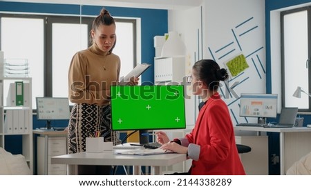 Business people talking about green screen on monitor, using computer with isolated chroma key and mockup template. Women colleagues working with blank copy space background on display.