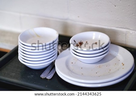 Stack empty and dirty dishes with food leftovers remnants on tray at restaurant or food court. Royalty-Free Stock Photo #2144343625