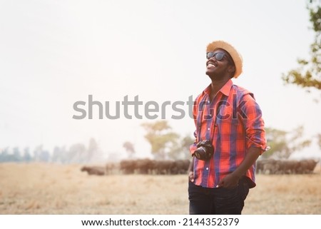 African photographer carries a camera and travels happily in Safari Africa with herds of buffalo in the background Royalty-Free Stock Photo #2144352379