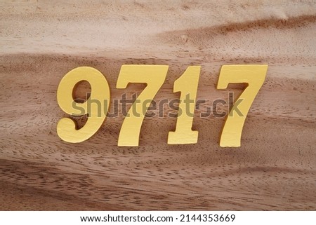 Wooden  numerals 9717 painted in gold on a dark brown and white patterned plank background.