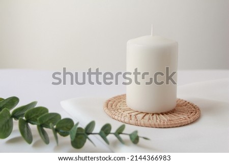 white candle with green eucalyptus on white background, modern and cozy  home