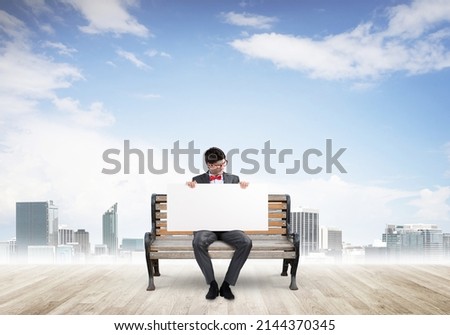 Young businessman holds a large white banner. sits on the bench