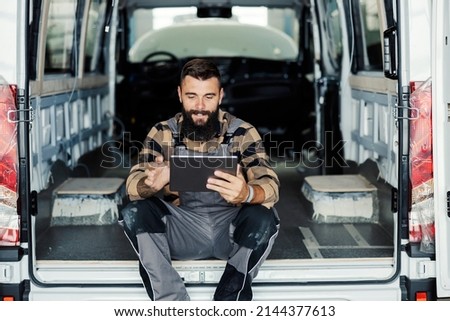 A vehicle factory sits in a pickup truck and using tablet and diagnostics a problem. Royalty-Free Stock Photo #2144377613