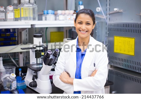 Closeup portrait, young smiling scientist in white lab coat standing by microscope. Isolated lab background. Research and development. Royalty-Free Stock Photo #214437766
