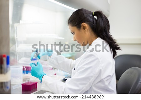 Closeup portrait, scientist holding 50 mL conical tube with blue liquid solution, performing laboratory experiments, isolated lab background. Forensics, genetics, microbiology, biochemistry Royalty-Free Stock Photo #214438969