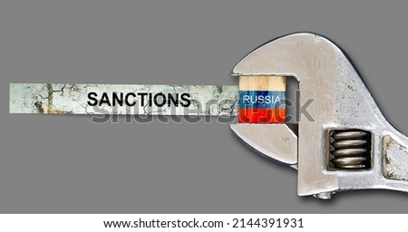 Sanctions. Flag of Russia on a wooden block, clamped with a wrench. Isolated on a gray background. Sanctions. Country isolation. economic blockade. Economy. Politics. Conflict. Royalty-Free Stock Photo #2144391931