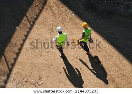 Directly above view of builders in hardhats and green waistcoats working at construction site Royalty-Free Stock Photo #2144393233