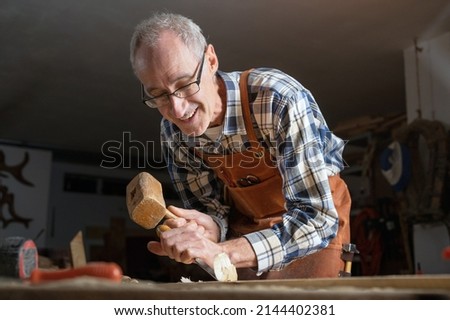 Skilled carpenter carving wood with hammer and chisel. High quality photography