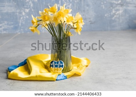 Heart in the form of puzzles with the colors of the flag of Ukraine with yellow flowers in a vase