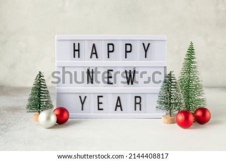 Lightbox with text HAPPY NEW YEAR with decorative Christmas trees. New year celebration