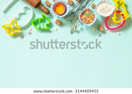 Baking or cooking background. Ingredients for Easter festive baking. Kitchen utensils, flour, brown sugar, eggs and butter on a light green background. Top view flat lay. Copy space.