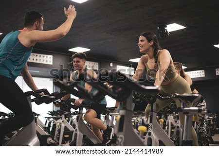 people on bikes in spinning class in modern gym, exercising on stationary bike. group of athletes training on exercise bike Royalty-Free Stock Photo #2144414989