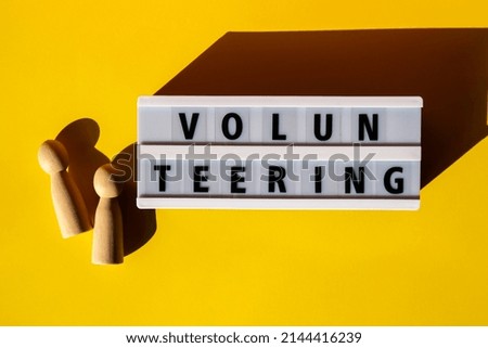 Lightbox with text VOLUNTEERING. Motivational Words Quotes Concept. Colorful yellow background. Minimalistic creative concept. Donation support