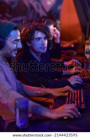 Concentrated young man sitting in esports bar and watching how guy completing game level Royalty-Free Stock Photo #2144423595