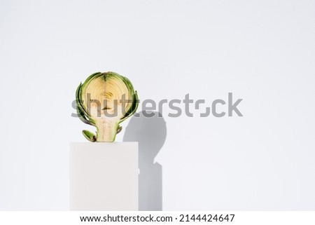 An artichoke cut in half standing on a white stand. Isolated. Copy space