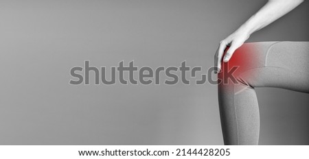 Banner with knee pain. Woman holding painful leg with red spot closeup. Arthritis, tendonitis, injuries. Health care, orthopedic problems and medicine concept. Copy space. Black and white. photo