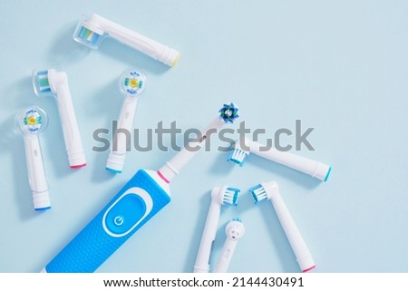 electric toothbrush and a lot of different multi-colored replaceable nozzles on blue background top view copy space Royalty-Free Stock Photo #2144430491