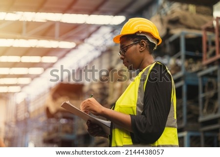 Engineer black women worker, Professional woman afican mechanical maintenance work in factory checking stock inventory in warehouse. Royalty-Free Stock Photo #2144438057