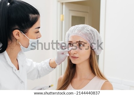 The cosmetologist wipes the patient's face after the procedure of filling the nasolacrimal furrow and mesotherapy around the eyes for a young beautiful girl. Modern cosmetology.